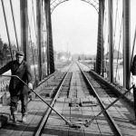 Two workers turn the railroad bridge with two “keys,” unlike their counterparts at the lower channel bridge who used only one. The Inn hotel’s swimming pool building, the “natatorium,” appears in the right distance. Railroad Bridge