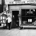 Bert and Amy Beaudoin’s ice cream parlor at 330 Bridge Street. Bert stands by his popcorn machine. As a striped pole identified a barbershop, bananas hung on a doorway signified groceries for sale, just as they appeared on Bert Mason’s entryway Bert and Amy Beaudoin’s ice cream parlor