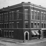The Charlevoix County Bank, built in 1903 at the Clinton Street corner. Offices and assembly rooms occupied the top two stories. Crane’s dry goods store wrapped around the bank, its two entrances marked by the upright awnings on both sides. The entire building burned to a shell on the bitterly cold morning of February 8, 1924. A faulty flue was thought to be the cause. No records were lost. The bank reopened the next day in a spare room down the street. A new bank, reduced by one story, was erected immediately. Charlevoix County Bank