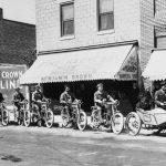 Benjamin Brown came to Charlevoix in 1898 from Petoskey where he had learned to make harnesses and other leather goods. In 1908 he established this harness and tackle, luggage and bicycle shop on Bridge Street near Mason Street in the 400 block. In 1912 Ben added a Harley-Davidson dealership. He appears at right with his mother in the sidecar. Second behind him, under the “N” on the awning, is Dan McSauba, one of the few Native Americans to wear a U. S. Postal Service uniform, and thought to be the only chief ever to deliver the U. S. mail. Benjamin Brown