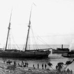 The narrow entrance to the channel from Lake Michigan has sometimes been a tricky target for vessels that aimed at the slot and missed, ending up stranded on the beach. Roaring seas, strong and changeable winds, pilot error, alcohol, and vanity have all been factors. Here the schooner Jenny Mullen lists to starboard on the Lake Michigan Beach. She was not considered seaworthy after she was righted and moved off the sand, and was towed to the ships’ graveyard at Lake Charlevoix’s Oyster Bay about three miles east of town where she was scuttled and sunk. Jenny Mullen beached on lake Michigan